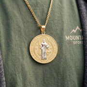 Close-up view of the two-tone gold Saint Benedict medallion paired with a gold cuban link chain on chest.