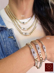 Female model showcasing a layered look with real 14K gold Monaco Chain™ Miami Cuban link necklaces and stacked pavé lock bracelets by Veka Jewelry.