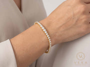 Lifestyle view of a woman wearing the 14K yellow gold graduated tennis bracelet on her wrist showcasing natural drape and 2.5mm to 5mm width proportion - Veka Jewelry.