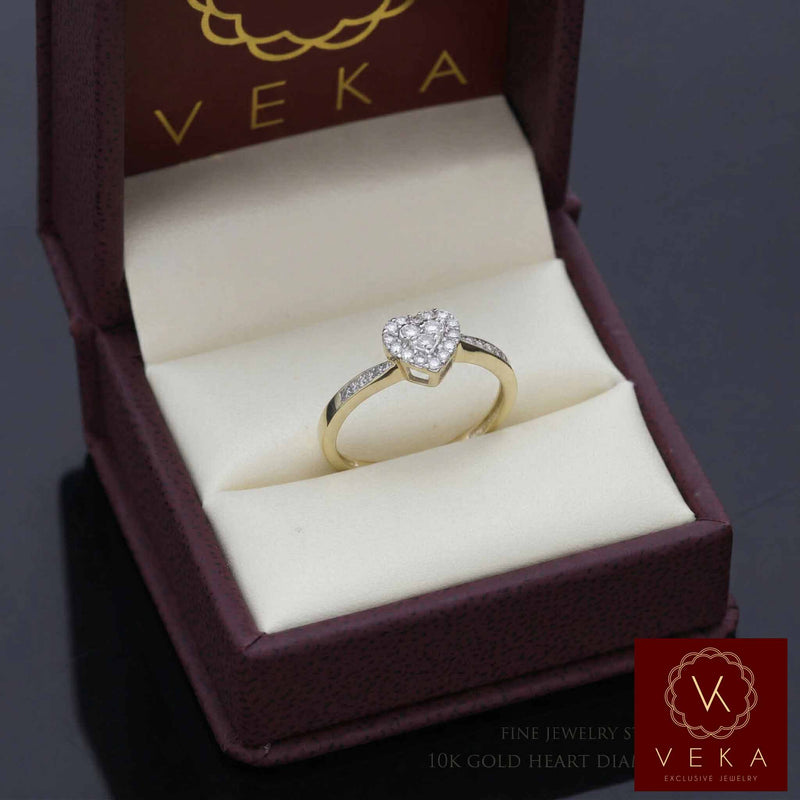 A detailed top-down view of the VEKA heart-shaped natural diamond ring, showing the 1/4 ctw sparkle of SI diamonds nestled in the cream cushion of the open maroon jewelry box with the gold VEKA logo