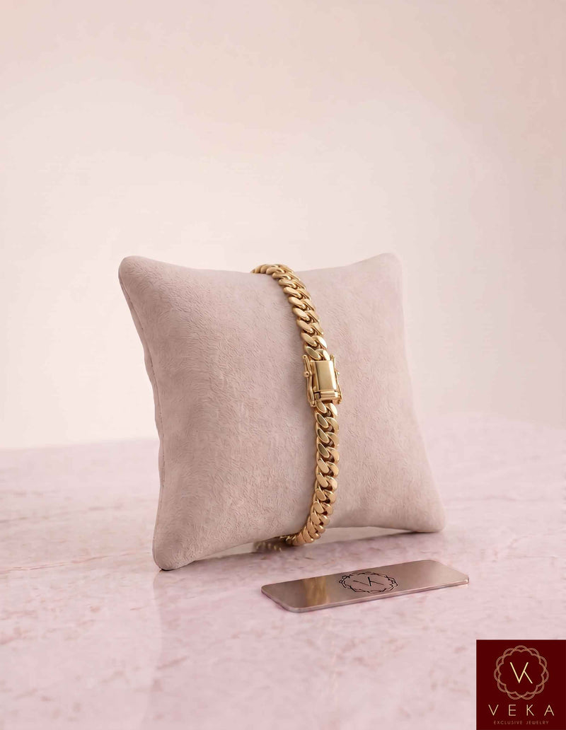 VEKA Jewelry 6mm Miami Cuban link bracelet in authentic 14K solid yellow gold displayed vertically on a beige velvet jewelry pillow