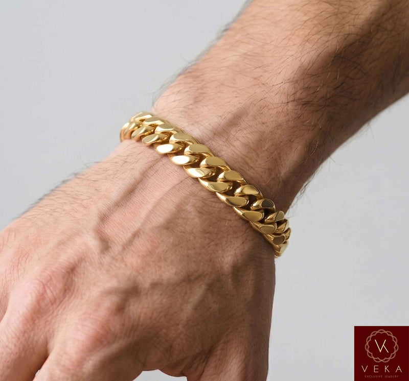 Man wearing a VEKA Jewelry 11mm 14K solid yellow gold Miami Cuban link bracelet on his wrist against a soft white gray background