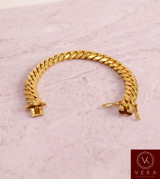 VEKA Jewelry 11mm Miami Cuban link bracelet in authentic 14K solid yellow gold displayed on a  luxurious marble stone with the Veka Jewelry Tag logo.