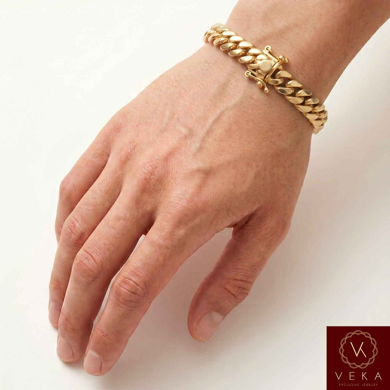 Man wearing a VEKA Jewelry 9mm 14K solid yellow gold Miami Cuban link bracelet on his wrist against a soft white beige background