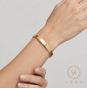 Female model gracefully wearing a classic yellow gold screw bangle bracelet on her wrist for Veka Jewelry