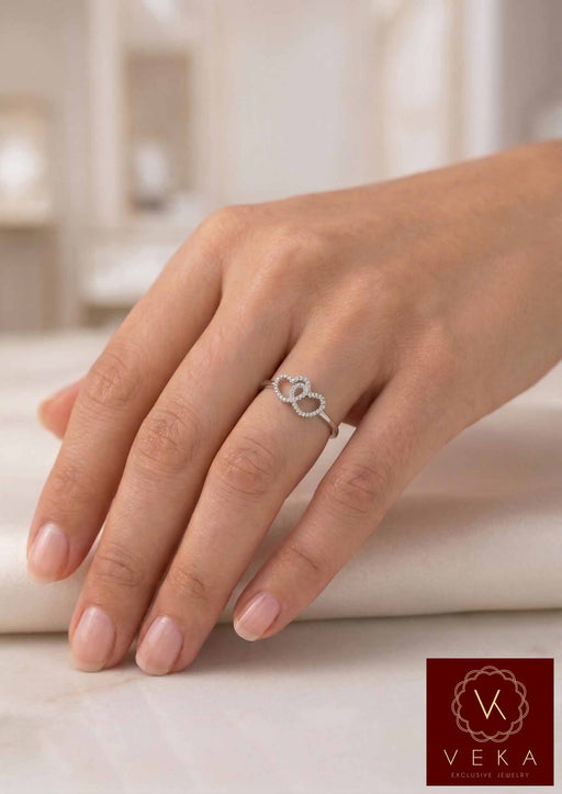 Close-up of a woman wearing the VEKA Jewelry interlocking double heart diamond ring in 14k white gold on her ring finger.