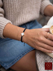 Woman wearing a VEKA Jewelry gold and mother of pearl clover macrame bracelet paired casually with a sweater and gold ring