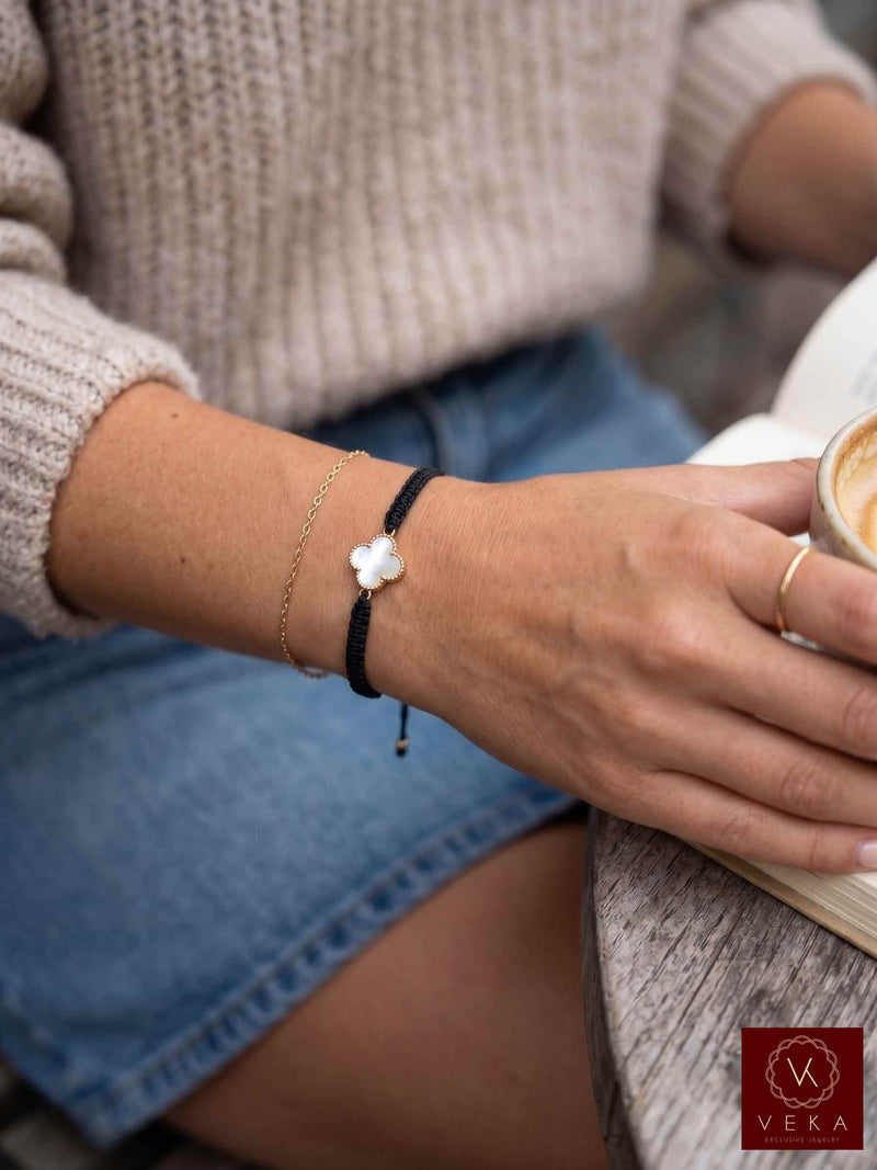 Woman wearing a VEKA Jewelry gold and mother of pearl clover macrame bracelet paired casually with a sweater and gold ring