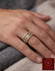 Close-up photograph of a man's hand wearing the VEKA Jewelry 10K gold and diamond kinetic spinning gear band ring on the ring finger