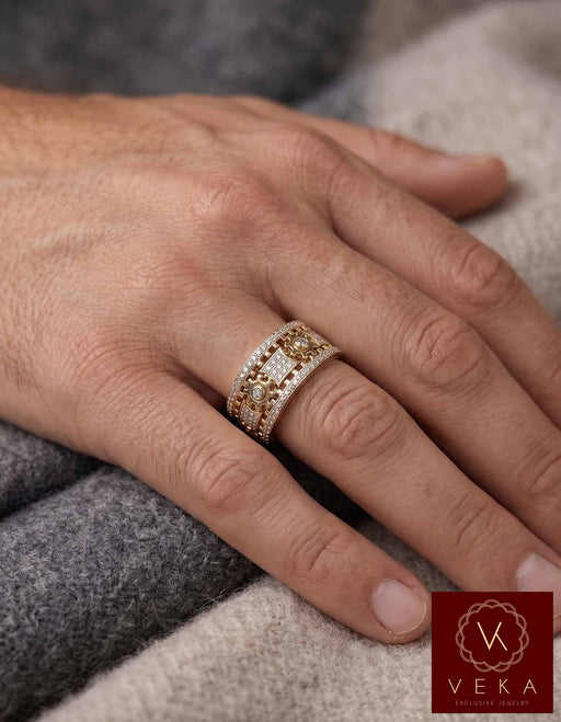 Close-up photograph of a man's hand wearing the VEKA Jewelry 10K gold and diamond kinetic spinning gear band ring on the ring finger