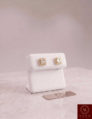 Veka Jewelry men's square halo stud earrings in 10k solid yellow gold with brilliant square and round moissanite stones, displayed on a white stand with a logo plaque.