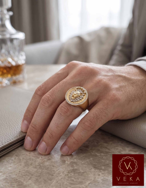 VEKA Exclusive Jewelry: Close-up on a man's hand wearing a large, ornate 14k yellow gold and diamond lion face signet ring, set against a luxurious lifestyle background with a leather mat and crystal