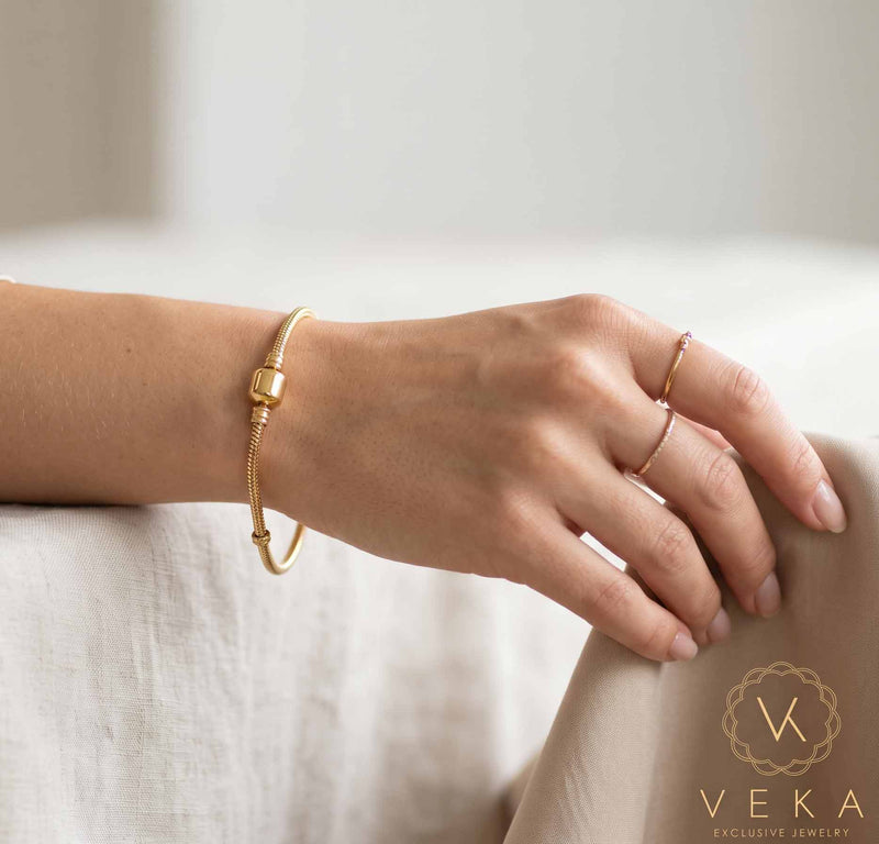 Close-up of female wrist showcasing an authentic 14K gold snake chain bracelet with barrel clasp - Veka Jewelry.