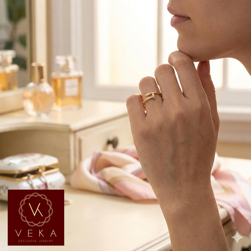 A woman in a feminine setting holding her chin, wearing a trendy 10K yellow gold nail design ring with cubic zirconia stones on her finger.