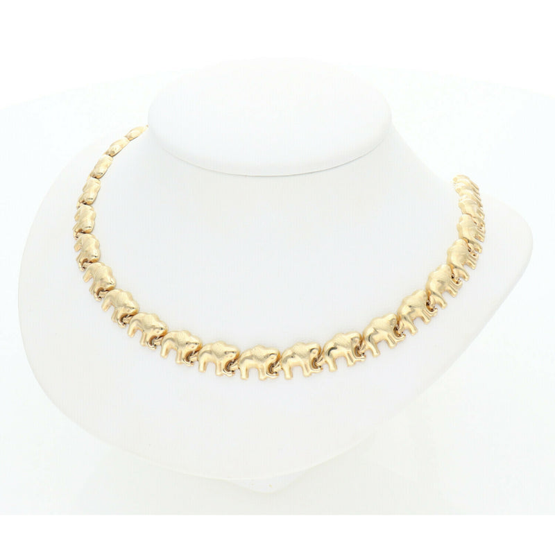 Top-down view of a high-polish 10K gold elephant link necklace on a minimalist white jewelry stand.