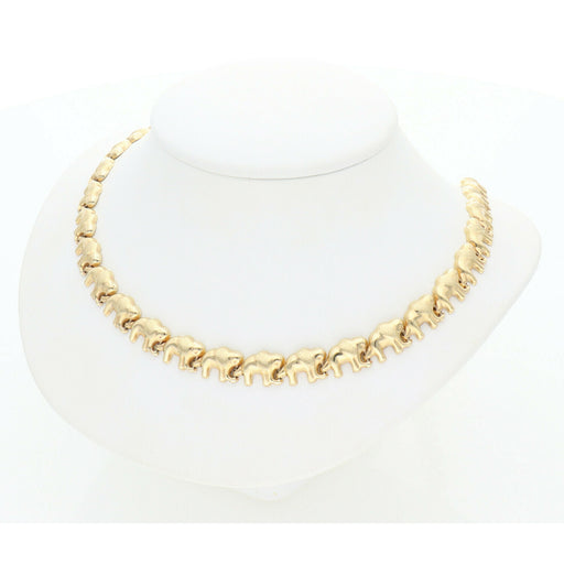 Top-down view of a high-polish 10K gold elephant link necklace on a minimalist white jewelry stand.