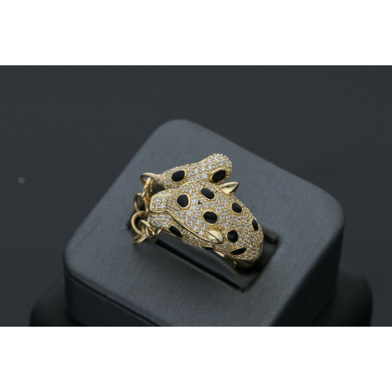 A 14 karat gold ring designed with a leopard motif, featuring small stones including green stones and a gold chain from face to tail on a dark background showing also black spots on the leopard.