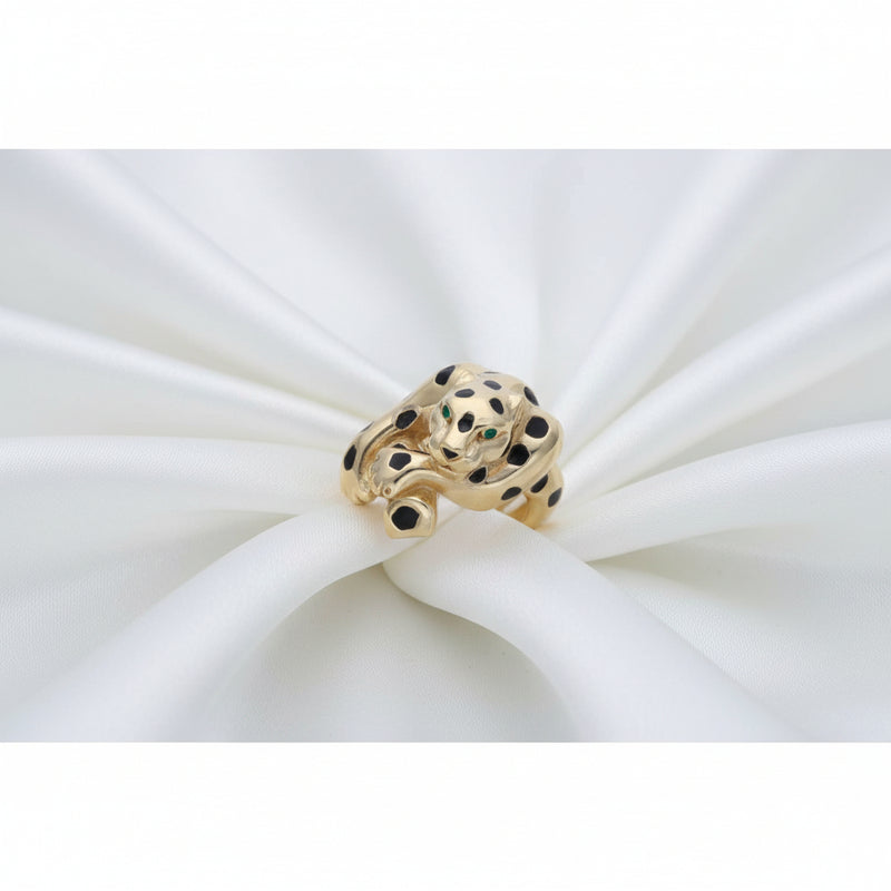 Close-up detail of a 14k gold feline leopard ring resting on soft white pleated silk fabric, highlighting the gold craftsmanship and enamel work.