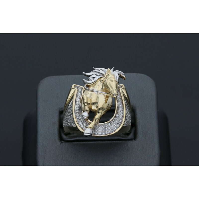 Detailed view of a men's heavy 14k yellow gold ring featuring a leaping horse with white gold accents set within a horseshoe paved with clear cubic zirconia stones in a black ring display