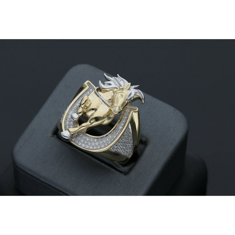 Detailed view of a men's heavy 14k yellow gold ring featuring a leaping horse with white gold accents set within a horseshoe paved with clear cubic zirconia stones on a black ring display