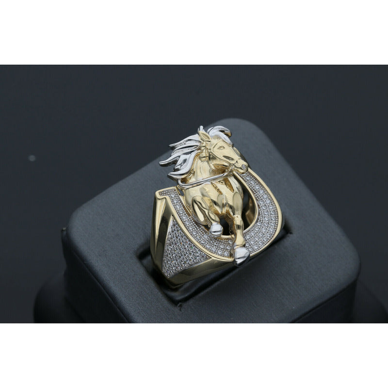 Detailed view of a men's heavy 14k yellow gold ring featuring a leaping horse with white gold accents set within a horseshoe paved with clear cubic zirconia stones on a black ring display