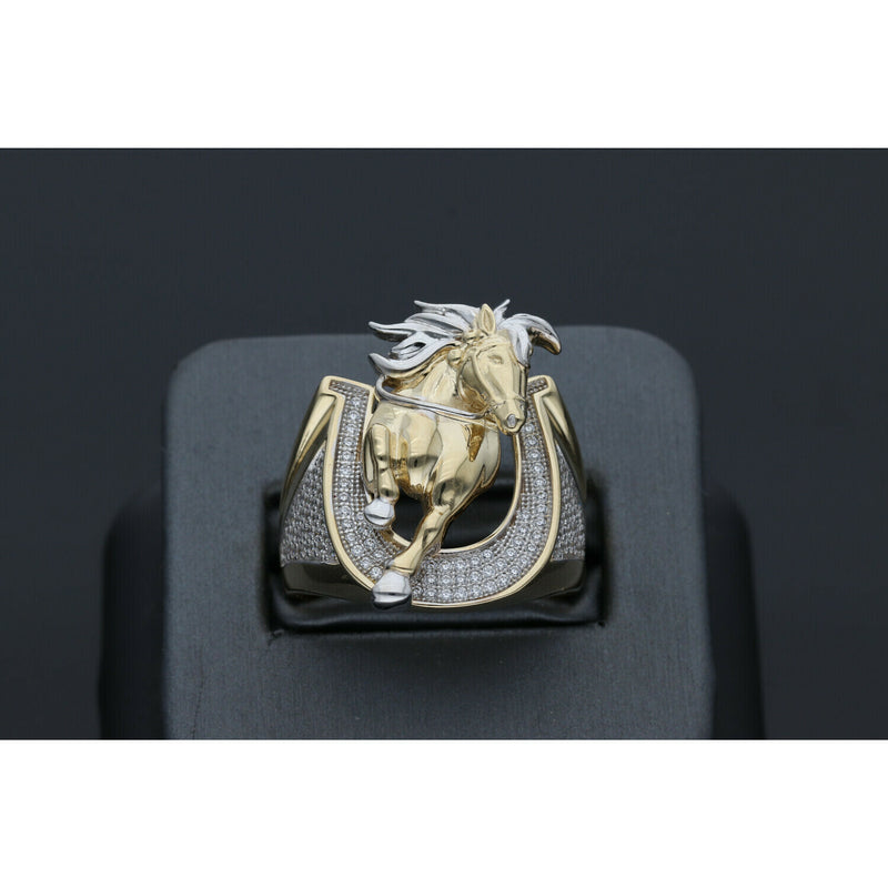 Detailed view of a men's heavy 14k yellow gold ring featuring a leaping horse with white gold accents set within a horseshoe paved with clear cubic zirconia stones on a black ring display